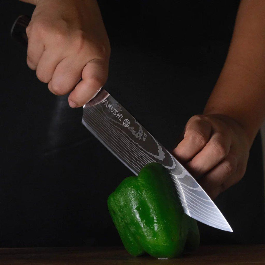 Cook using a pinch grip on a Yakushi Japanese chef knife while slicing a green bell pepper on a wooden board