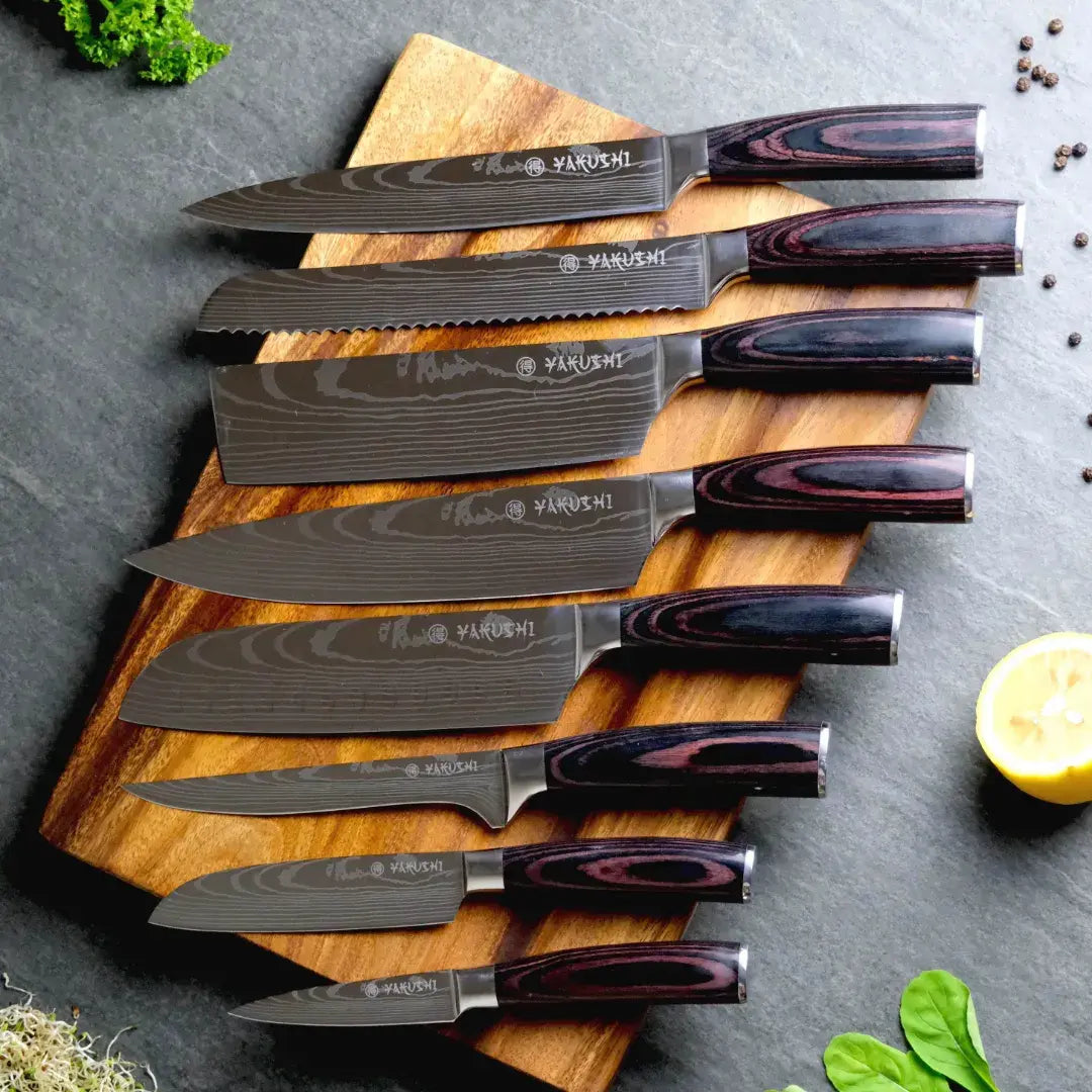 Yakushi Japanese knife collection on a wooden board, including full-size and compact Santoku blades
